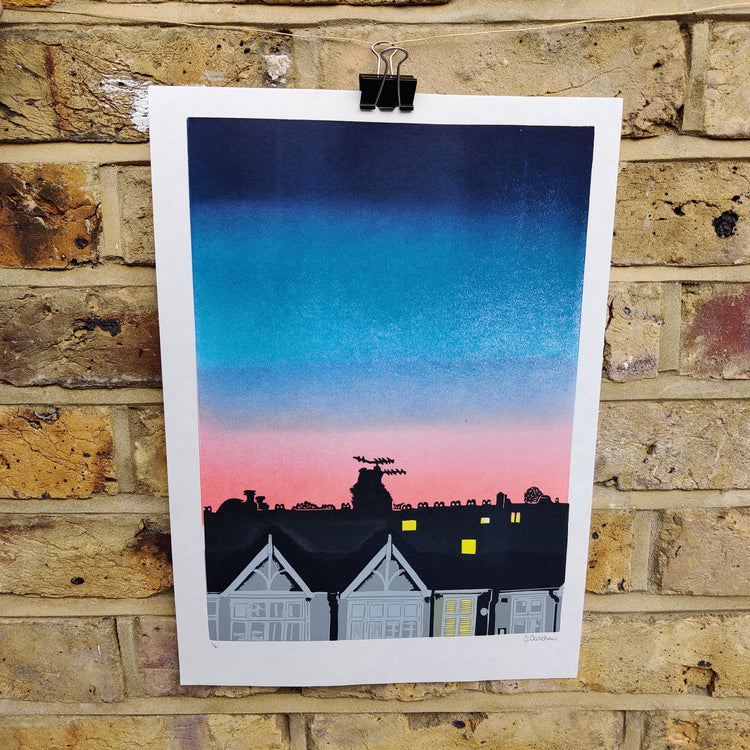 Full print of Over the Road, lino print of a row of terraced houses against a blue and pink sky background